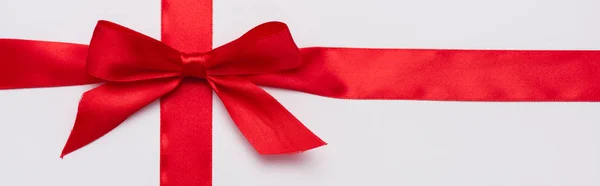 Panoramic shot of satin ribbon with red decorative bow isolated on white — Stock Photo