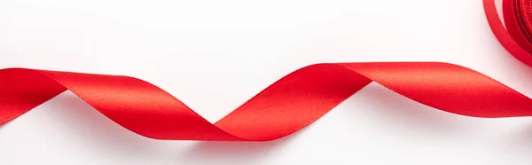 Plan panoramique de ruban bouclé rouge sur blanc avec espace de copie — Photo de stock