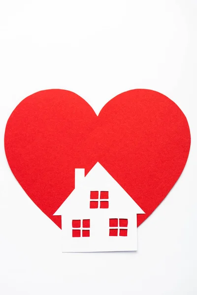 Бумажный дом рядом с красным сердцем изолирован на белом — стоковое фото