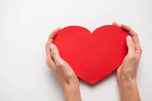 Cropped view of woman holding red heart shape paper cut on white — Stock Photo