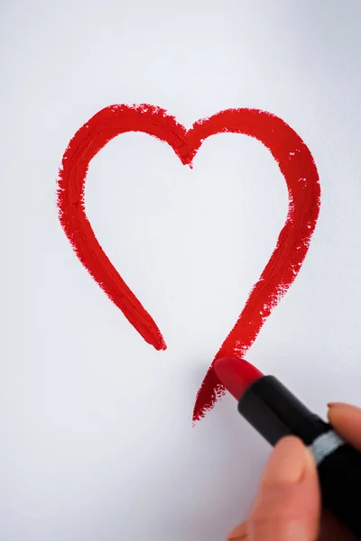 Vista recortada de la mujer dibujando corazón con lápiz labial rojo aislado en blanco - foto de stock