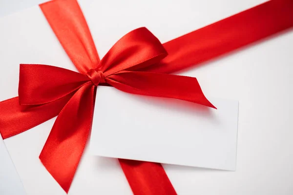 Blank card near red ribbon with satin bow on white — Stock Photo
