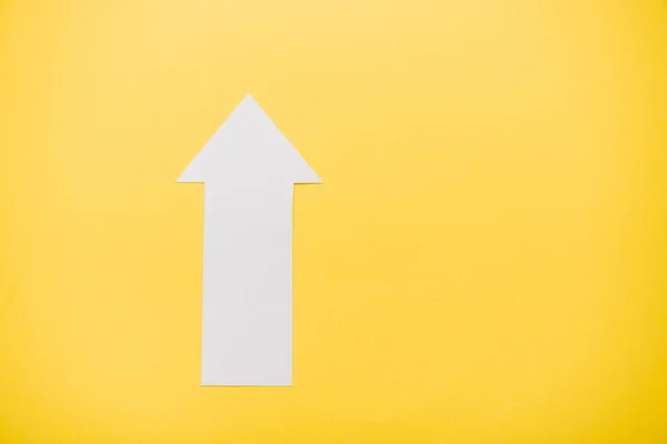 Top view of white arrow isolated on yellow with copy space — Stock Photo