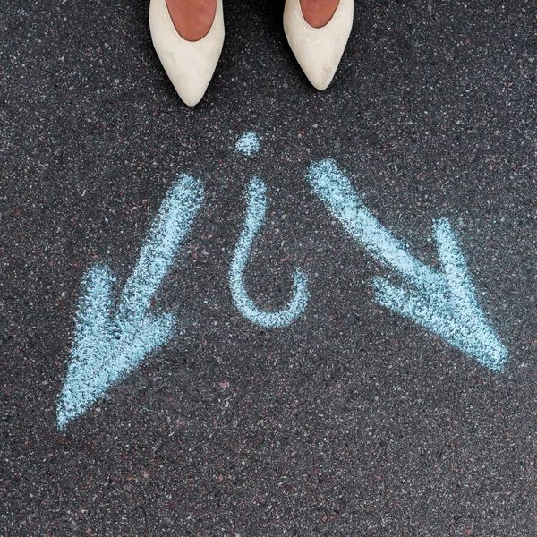 Top view of woman standing near blue directional arrows on asphalt — Stock Photo