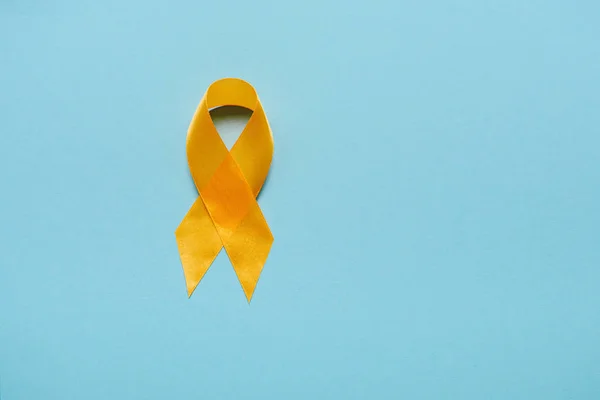 Vista superior de la cinta de conciencia amarilla sobre fondo azul, concepto de prevención del suicidio - foto de stock