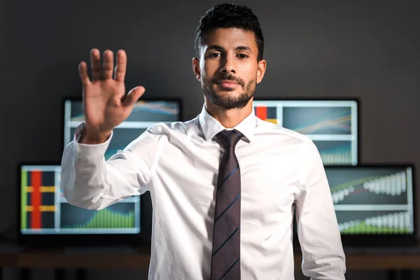 Bi-racial comerciante saludando y mirando a la cámara en la oficina - foto de stock