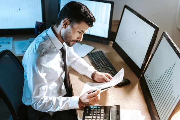 Vista de ángulo alto del comerciante bi-racial mirando el papel - foto de stock