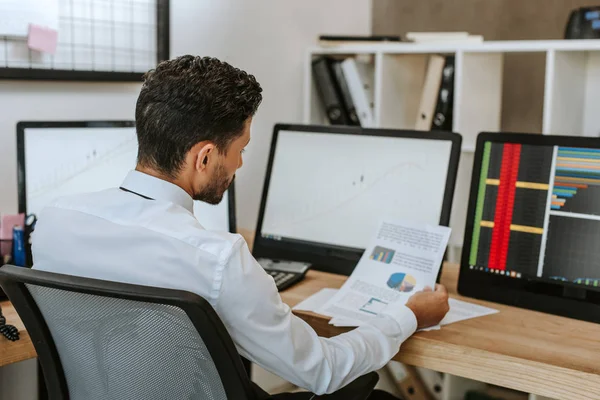 Selective focus of bi-racial trader looking at paper in office — Stock Photo