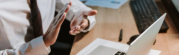 Plano panorámico del comerciante bi-racial aplaudiendo y sentado en la mesa - foto de stock