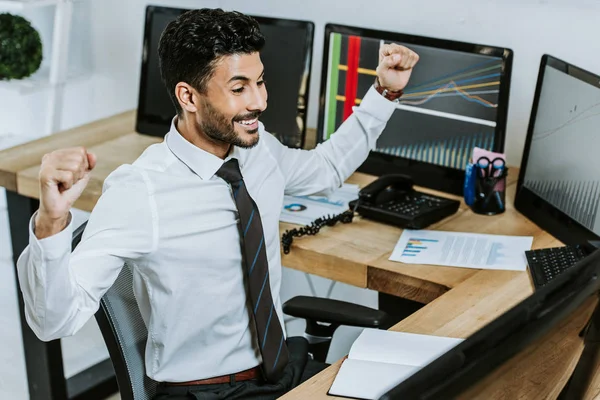 Hochwinkelaufnahme eines lächelnden bi-rassischen Händlers, der auf den Computer blickt und Ja-Geste zeigt — Stockfoto