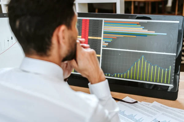 Selective focus of bi-racial trader looking at computer with graphs — Stock Photo