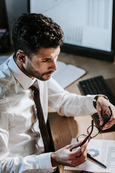 High angle view of bi-racial trader holding glasses and looking away — Stock Photo