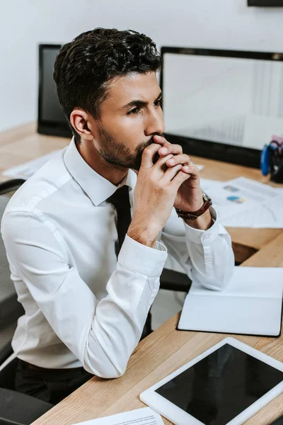 Pensive bi-racial trader sitting at table and looking away — Stock Photo