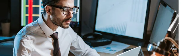 Tiro panorámico de comerciante bi-racial en gafas mirando a la computadora - foto de stock