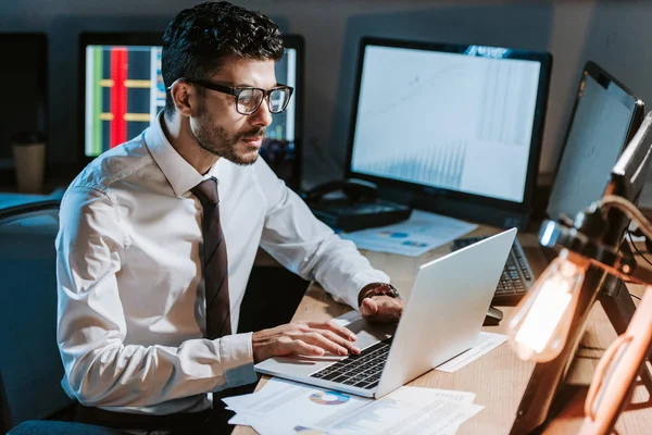 Bi-racial trader using laptop and sitting at table in office — Stock Photo