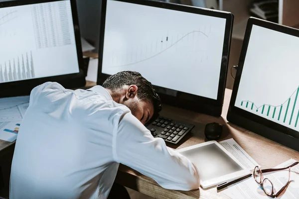 Vista ad alto angolo del commerciante bi-razziale dormire vicino a computer con grafici — Foto stock