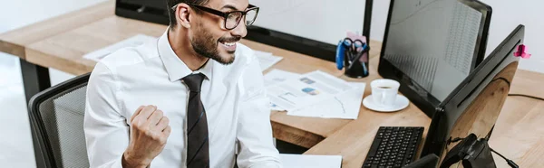 Tiro panorâmico de comerciante sorrindo olhando para o computador e mostrando sim gesto — Fotografia de Stock