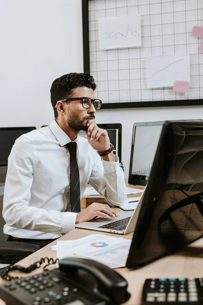 Pensive bi-racial trader sitting at table and looking away — Stock Photo