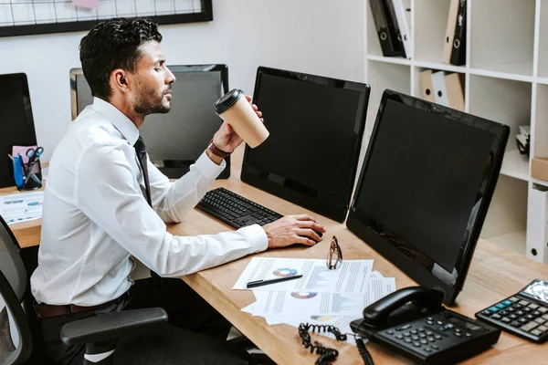 Side view of bi-racial trader sitting at table and drinking coffee — Stock Photo