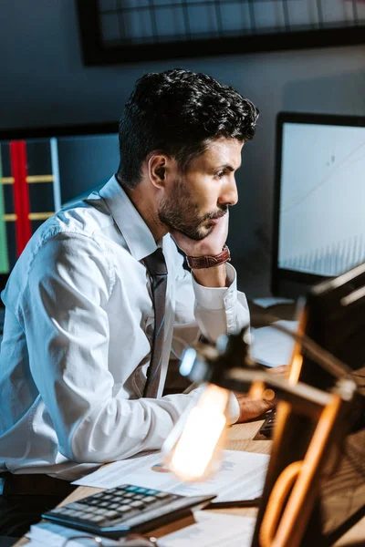 Side view of bi-racial trader sitting at table and looking away — Stock Photo