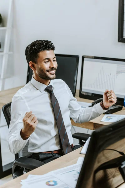 Sorrindo comerciante bi-racial mostrando sim gesto e sentado à mesa — Fotografia de Stock