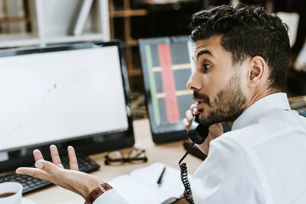 Side view of bi-racial trader talking on telephone in office — Stock Photo