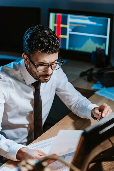 High angle view of bi-racial trader looking at paper and sitting at table — Stock Photo