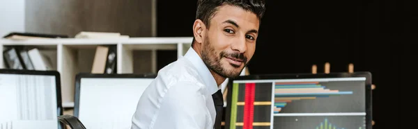 Panoramic shot of smiling bi-racial trader looking at camera — Stock Photo