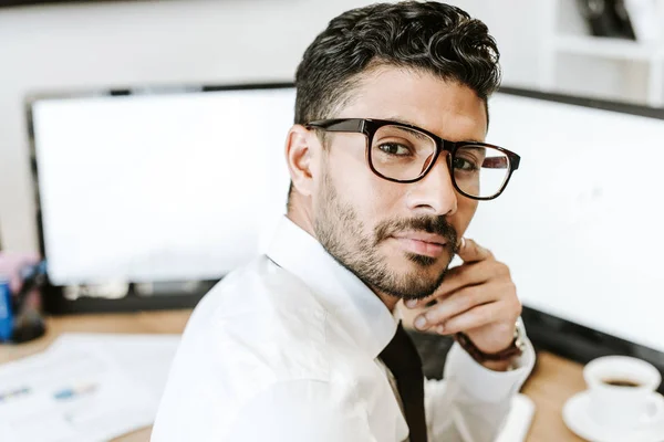 Zweirassiger Händler mit Brille blickt im Büro in die Kamera — Stockfoto