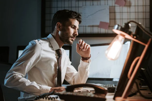 Vista lateral de bonito comerciante bi-racial usando computador e sentado à mesa — Fotografia de Stock