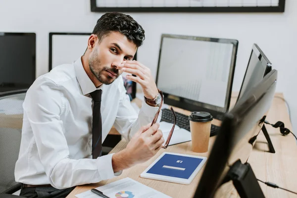 KYIV, UKRAINE - 10 OCTOBRE 2019 : Cher commerçant bi-racial tenant des lunettes et une tablette numérique avec l'application Facebook — Photo de stock