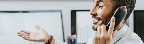 Colpo panoramico di sorridente commerciante bi-razziale parlando al telefono — Foto stock