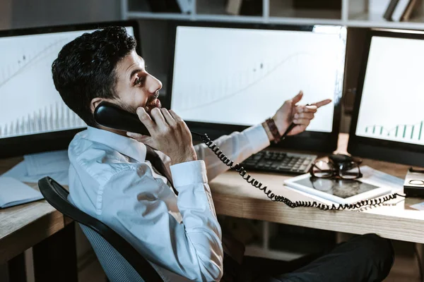 Smiling bi-racial trader talking on telephone and sitting at table — Stock Photo