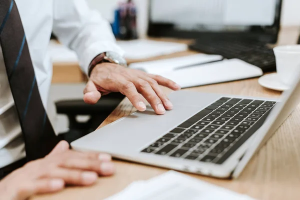 Cropped view of bi-racial trader suing laptop in office — Stock Photo