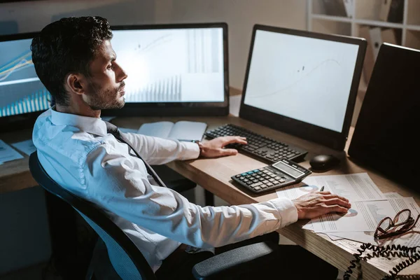 Vista lateral do comerciante bi-racial sentado à mesa e olhando para o computador — Fotografia de Stock