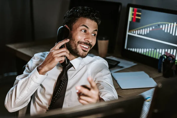 Smiling bi-racial trader talking on telephone and looking away — Stock Photo