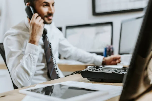 Selective focus of smiling bi-racial trader talking on telephone in office — Stock Photo