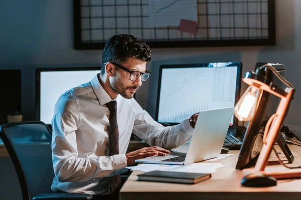 Trader bi-razziale utilizzando il computer portatile e seduto a tavola in ufficio — Foto stock