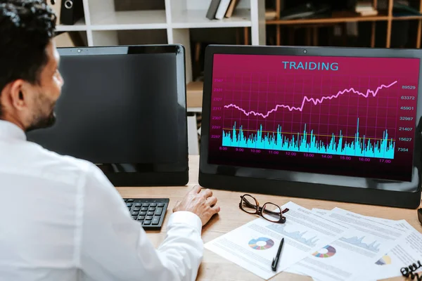 Abgeschnittene Ansicht von bi-racial Trader mit Computer mit Schriftzug Handel — Stockfoto