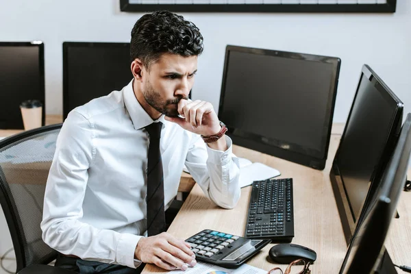 Nachdenklicher Händler, der am Computer sitzt und am Tisch sitzt — Stockfoto