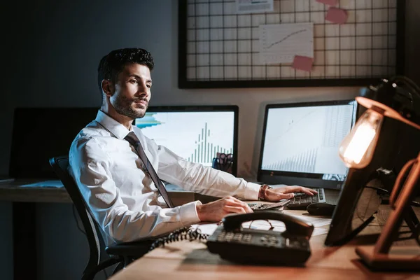 Bi-racial trader sitting at table and looking away in office — Stock Photo