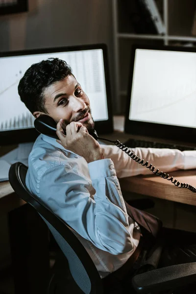 Smiling bi-racial trader talking on telephone and looking at camera — Stock Photo