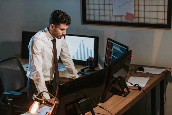 Visão de alto ângulo de comerciante bi-racial em pé perto de computadores no escritório — Fotografia de Stock