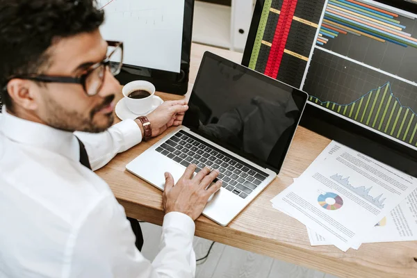 Selective focus of bi-racial trader using laptop and looking away — Stock Photo