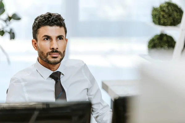 Selective focus of handsome bi-racial trader looking away in office — Stock Photo