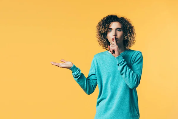 Lockiger Teenager zeigt shh Geste und zeigt mit der Hand zur Seite isoliert auf gelb — Stockfoto
