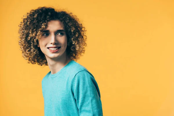 Sorridente adolescente riccio guardando lontano isolato sul giallo — Foto stock