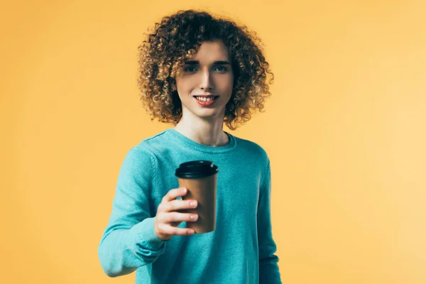 Selektiver Fokus eines lächelnden, lockigen Teenagers, der Kaffee in Pappbecher hält, isoliert auf gelb — Stockfoto