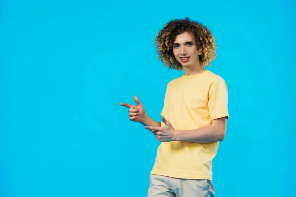 Adolescente encaracolado positivo apontando com os dedos isolados em azul — Fotografia de Stock
