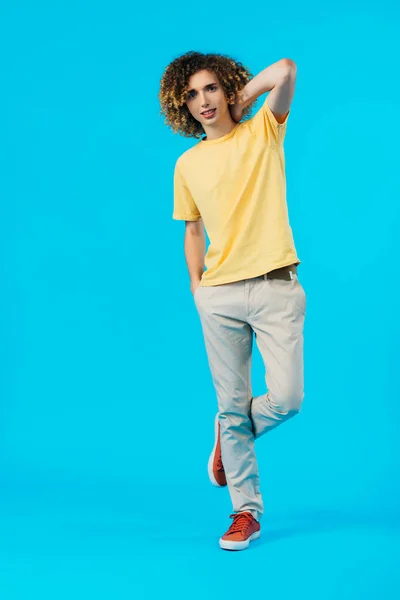 Longitud completa vista de rizado adolescente posando aislado en azul - foto de stock